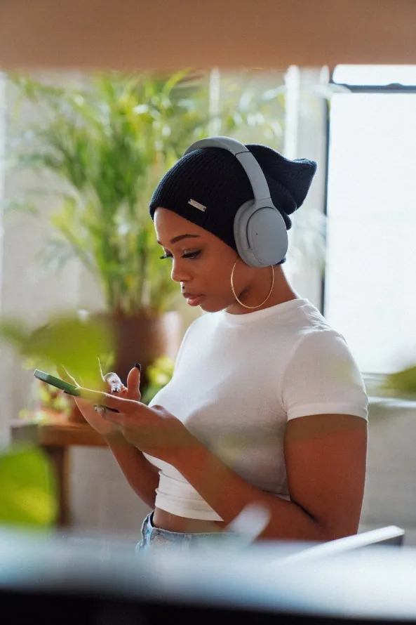 A woman with headphones checking her phone