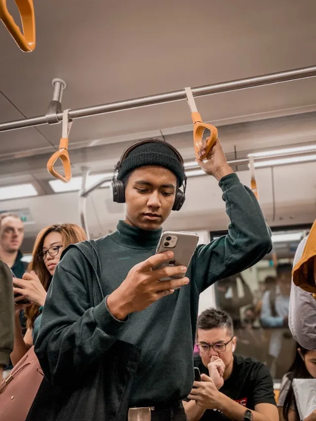 A young man using the Nirra app on a busy bus